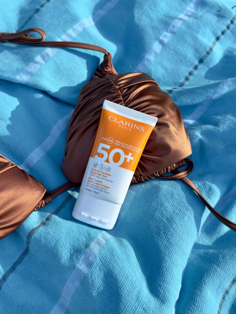 Sonnencreme auf Strandtuch mit Bikini